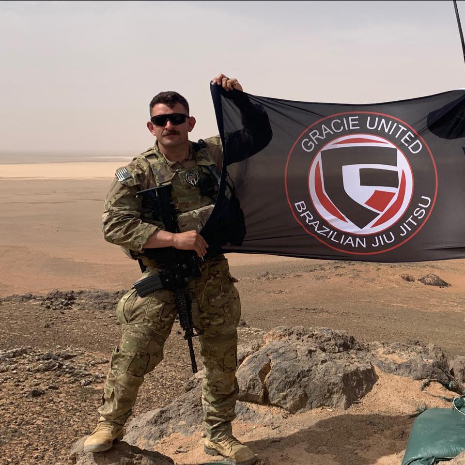 Gracie United - Team Jucao Red River Student holding flag of Gracie united logo